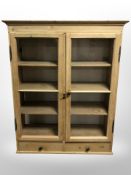 An early-20th century glazed pine double-door cabinet, 101cm wide x 35cm deep x 125cm high.