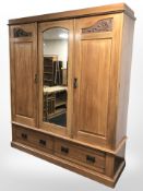 An Art Nouveau satin walnut triple wardrobe with central mirrored door,