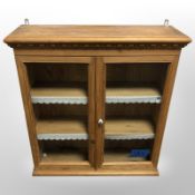 A 20th-century glazed pine double-door wall cabinet, 66cm wide x 21cm deep x 72cm high.