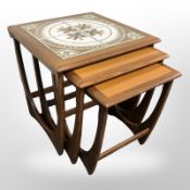 A 20th-century teak nest of three tables with tile-inset tops, width 50cm.