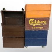 Six vintage painted pine bottle crates, some on castors.