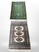 A Turkish rug on green ground depicting an urn of flowers, 118cm x 66cm,