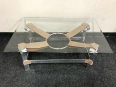 A contemporary bevel glass rectangular coffee table on chrome and stitched tan leather support,