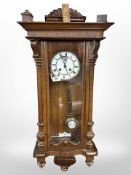 An early 20th century oak wall clock with enamelled dial,