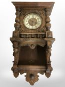 An early-20th century continental carved oak eight-day wall clock with enamelled dial, height 73cm.