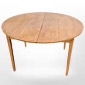 A 20th century teak extending dining table diameter 122 cm and one leaf