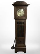 An early 20th century carved oak grandmother clock with silvered dial, with pendulum,