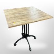 A pine square patio table on painted metal support,