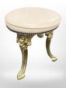 A gilt metal tripod stool with cream leather top,