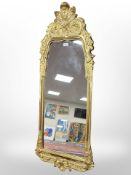 A mirror in ornate gilt composition frame, overall dimensions including frame 128 cm x 46 cm.