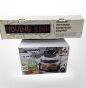 A Daewoo air fryer, and a moving message electronic display sign, both boxed.