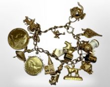 A 9ct gold charm bracelet set with many charms and two silver-gilt coins, 69.6g.