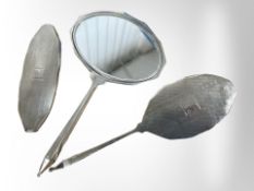 A silver dressing table mirror and two brushes with engine turned decoration, mirror 23.5cm long.