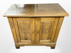 A 20th-century carved-oak double-door cabinet, 89cm wide x 45cm deep x 83cm high.