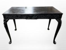 A heavily carved and ebonised Eastern side table on cabriole legs,