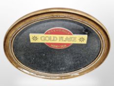 An oval mirror with applied Gold Flake sticker,