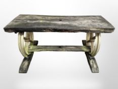 A weather teak outdoor table on gilt metal cartwheel supports,