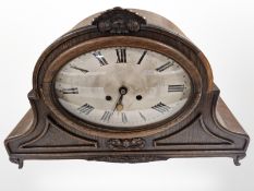 A 1920s carved oak bracket clock with pendulum and key, striking on a gong, width 49cm.