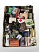 A shallow tin containing novelty lighters, matchbooks, etc.