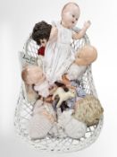 A wicker doll's basket containing various dolls.