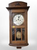 An early-20th century oak wall clock with silvered dial, length 70cm.