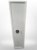 A steel gun cabinet with slots for five guns plus ammunition storage above, with two keys,