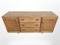 An Ercol elm low sideboard on castors,