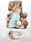 A wicker doll's basket and various dolls including one bisque-headed doll.
