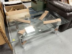A contemporary glass rectangular coffee table on chrome and stitched leather support,