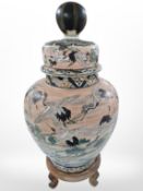 A large oriental earthenware temple jar and cover on wooden stand (as found), height 61cm.