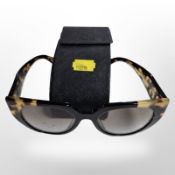 A pair of Prada sunglasses in travel case.