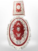 A Chinese oval rug on red ground,