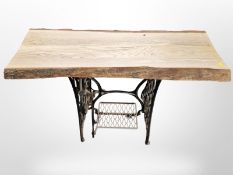 A Singer cast iron treadle sewing machine base with later rustic wooden top,