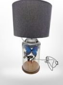 A contemporary glass table lamp contained three butterfly specimens,