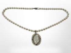 A pearl necklace with pearl mounted mother of pearl cameo pendant and silver clasp, length 43 cm.