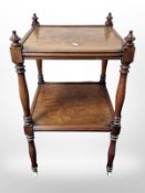 A Victorian mahogany two tier what not on castors,