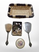 A wicker basket containing dressing table, brush, mirror and pot,