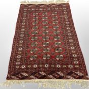 A Turkoman rug, Afghanistan, with three columns of guls against a madder central field,