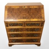 A reproduction walnut bureau in the George III style,