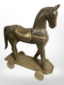 A painted and gilt wooden horse on wheels,