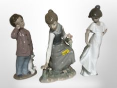 A Lladró figure of a girl picking flowers and two Nao figures of children, tallest 22cm.