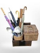 A faux leather trunk containing wicker basket, assorted umbrellas, two angle-poise lamps,