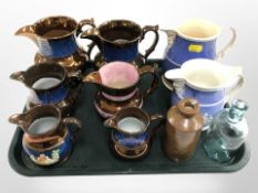 A group of copper lustre jugs, two further blue and white jugs, stoneware bottle and a glass bottle.