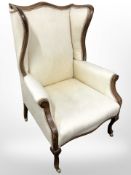 A Victorian mahogany framed wing back armchair in cream floral upholstery on brass castors,