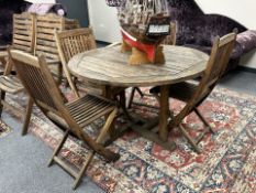 A plantation teak circular garden table, diameter 120cm, together with a set of four folding chairs.