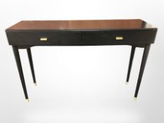 A modern ebonised two drawer side table on tapered brass capped legs,