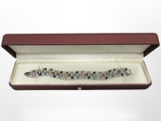 A white metal bracelet set with multicoloured synthetic stones.