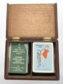 A teak playing card box containing several sets of cards.