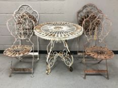 A weathered wrought metal circular garden table and four chairs