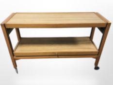 A teak effect two tier trolley on castors,